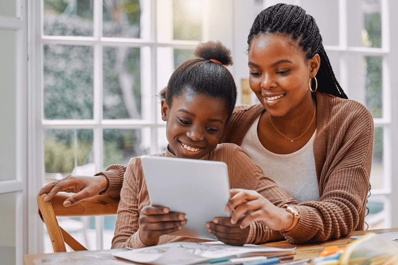A parent and child looking at a school report together on a tablet